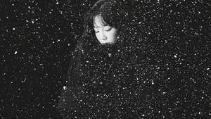 一位閉著眼睛的女子站在黑暗天空下飄落的雪中。 — 咒術回戰 壁紙