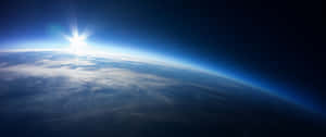 從太空看地球上的日出，帶有藍色大氣和白雲。 — 太空 壁紙