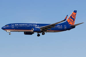 Sun Country Airlines 飛機在晴朗的藍天下飛行，起落架已放下