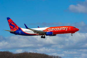 Sun Country Airlines飛機放下起落架，在藍天白雲中低飛。