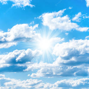 太陽穿過白雲在藍天中明亮地照耀
