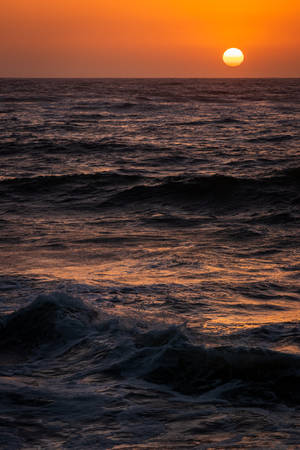 海上日落，波浪上泛著橙色光芒