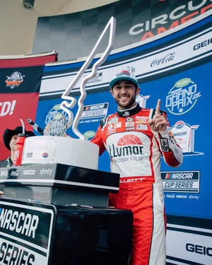 NASCAR車手在德州大獎賽頒獎台上手持獎盃慶祝勝利。