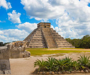 多雲天空下的古代瑪雅金字塔，帶有石雕和綠色植物。 — 建築 壁紙