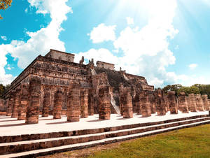古代瑪雅神廟遺址，有石柱和金字塔，背景是晴朗藍天。 — 建築 壁紙