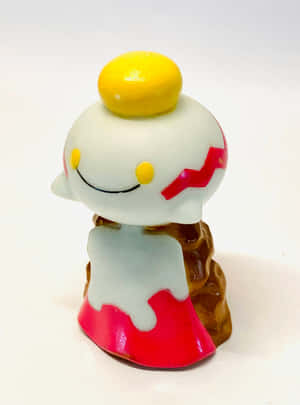 一個細小的白色塑膠玩具公仔，有黃色頂部和紅色細節。