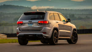 銀色Jeep Grand Cherokee Trackhawk在賽道上，背景有山巒。