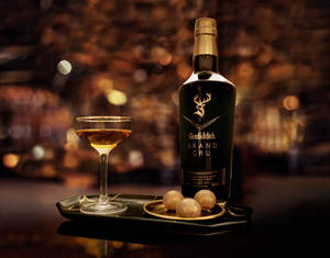 Glenfiddich Grand Cru 威士忌酒瓶、雞尾酒杯和冰球在酒吧托盤上。