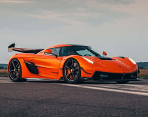 橙色Koenigsegg hypercar在瀝青賽道上於日落時分