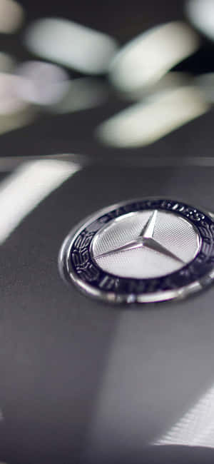Mercedes-Benz 標誌在黑色引擎蓋上，背景模糊。