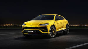 黃色林寶堅尼 Urus SUV 夜間停泊，背景有城市燈光。