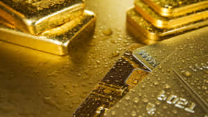 堆疊的金條和信用卡，金色表面上帶有水珠。 — 金色美學 GIF 壁紙