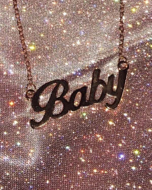 一條玫瑰金項鍊，上面有草書 'Baby' 字樣，背景是閃粉。 — 美學 壁紙
