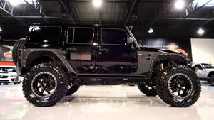 黑色升高底盤的Jeep Wrangler在陳列室中展示，配有反光地板和天花燈。