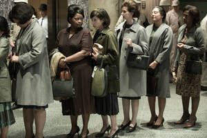 穿著1960年代大衣和高跟鞋的女性，帶著嚴肅的表情在室內排隊站立。
