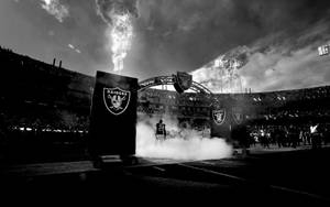 Raiders 美式足球運動員在夜間體育場穿過煙霧