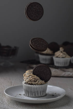 朱古力紙杯蛋糕上懸浮著 Oreo 餅乾，放在白色碟上。