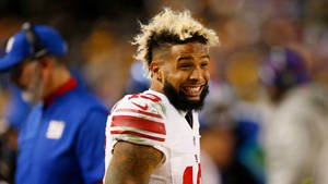 NFL美式足球運動員微笑，漂白頭髮和鬍鬚，在夜間球場。