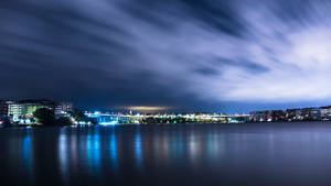 夜景城市景觀，橋樑燈光在水面上反射，天空有條紋雲。