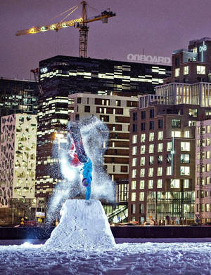 滑雪板手在夜間城市雪堆上做倒立技巧