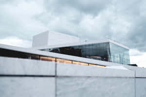 陰天天空下，現代白色玻璃建築，帶有溫暖的室內燈光。 — 建築 壁紙