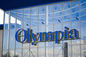 現代玻璃建築物，帶有藍色Olympia標誌同反射中飛緊嘅雀仔。