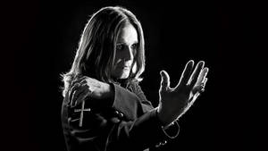 Ozzy Osbourne 黑白照片，帶十字架和戒指，背景深色。