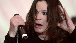 Ozzy Osbourne 對著麥克風唱歌，表情專注。