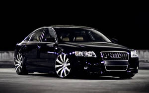 黑色奧迪轎車配備定制輪圈，夜間停放在城市環境中。 — Audi R8 GIF 壁紙