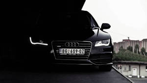 黑色奧迪汽車，車頭燈發光，停放在都市環境中。 — Audi R8 GIF 壁紙