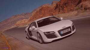 白色奧迪R8在沙漠公路上疾馳，旁邊有紅色懸崖，日落時分。 — Audi R8 GIF 壁紙