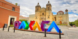 陽光明媚的廣場上，歷史悠久的大教堂前色彩繽紛的OAXACA字母。 — 墨西哥 GIF 壁紙