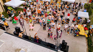 人群在戶外日間節日中，在舞台和食物桌旁跳舞。 — 音樂 GIF 壁紙