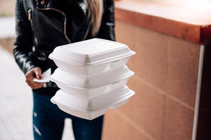 喺城市行人路上攞住疊起咗嘅外賣盒嘅人。