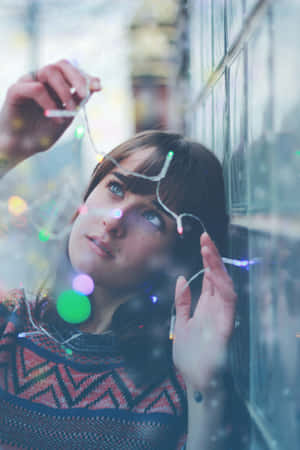 女性透過雨窗向上看，彩色燈光反射