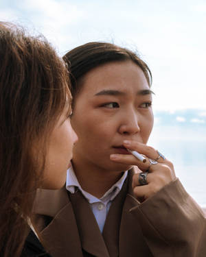 兩位女性在戶外，其中一位將香煙靠近嘴唇