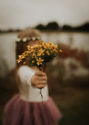 一個穿著粉紅色芭蕾舞裙的孩子遞出一束黃色花束。 — 女孩 壁紙