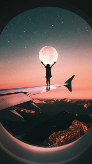 人站在飛機機翼上，在暮色中伸手觸摸山上的月亮