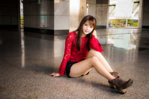 身穿紅色蕾絲上衣的年輕女士坐在室內拋光地板上