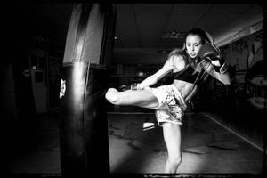 女拳擊手在健身房中以黑白燈光踢腿的瞬間。