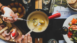 Cheese fondue with potatoes meats and salad on a wooden table. — 薯條 壁紙