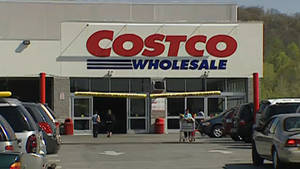 Costco Wholesale商店入口，有購物者和停泊的汽車在陽光明媚的日子。