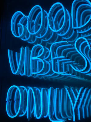 在黑暗房間中，藍色霓虹燈牌顯示「good vibes only」。