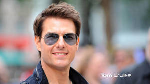 湯告魯斯戴著飛行員太陽眼鏡，在戶外微笑。