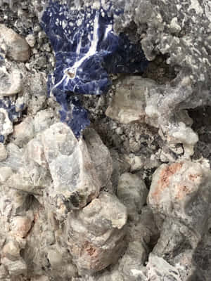 粗糙灰色岩石中藍色礦脈的特寫，帶有橙色斑點。