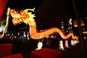 夜間街頭節日中，一個大型發光龍燈籠，附近有兔子造型。 — 明亮 壁紙