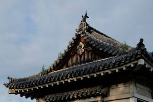 傳統日本寺廟屋頂，彎曲屋簷和裝飾瓦片，在陰雲天空下。