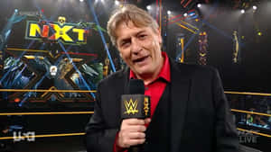 WWE NXT 評論員在現場直播期間於摔角擂台上手持麥克風。
