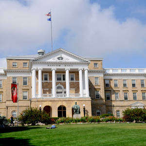 多雲天空下，帶有白色柱子和旗幟的Bascom Hall大學建築。