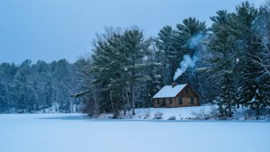 結冰湖邊的雪中小屋，煙囪冒煙